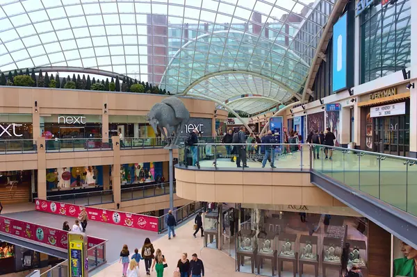 Shoppers on the levels of a large glass-roofed shopping centre