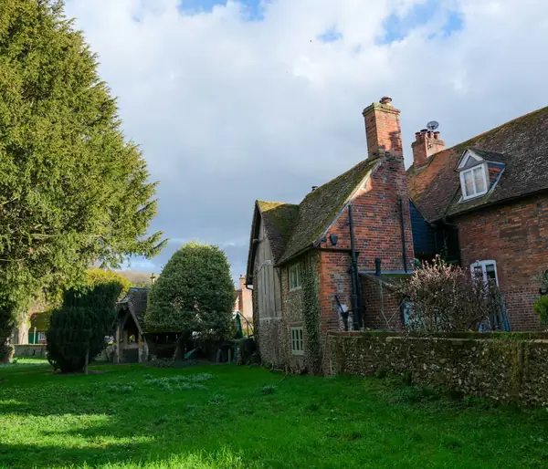 Old brick manor house with tall chimneys beside a lawn