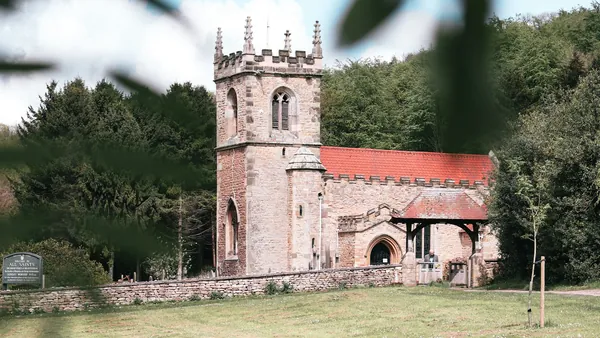 Stone parish church with a battlemented tower and red tiled roof