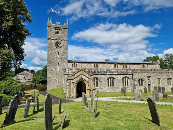 Medieval stone church with a square tower above a churchyard