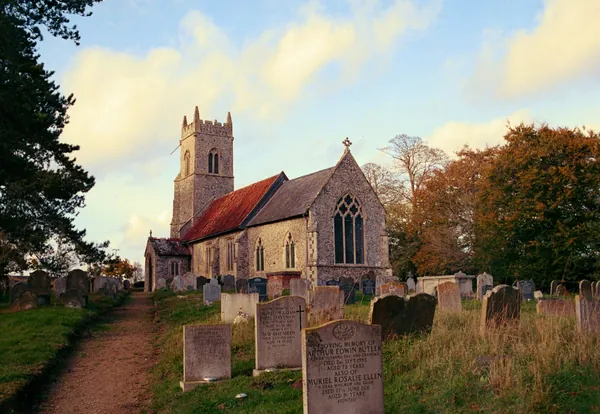 Old flint church with a square tower behind a churchyard path