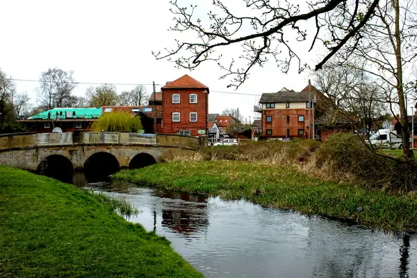 River flowing under an old stone bridge with houses behind