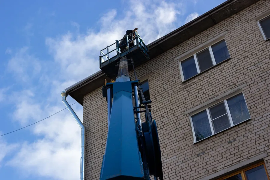 Mobile access platform raised to the eaves of a brick building, one way of reaching chimneys and flashing for repair in Dartford