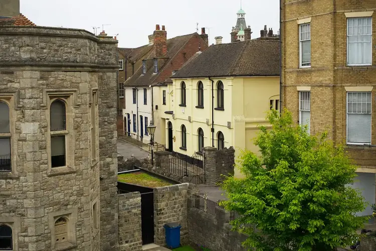 Older stone and brick buildings with tiled roofs and chimneys on a north Kent street, the kind of period roofs that cost more to repair
