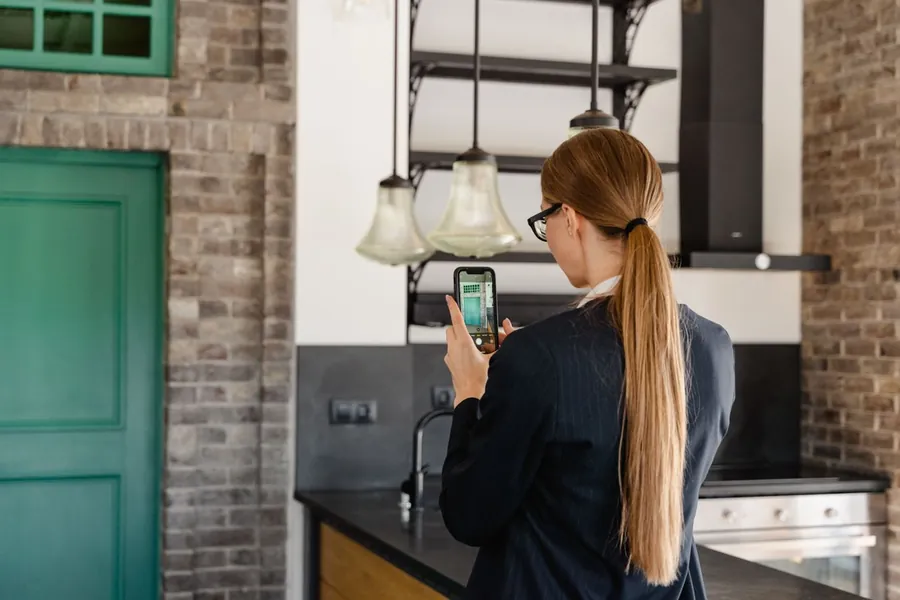 Woman taking a photo on her smartphone inside a house, recording damage for a storm insurance claim