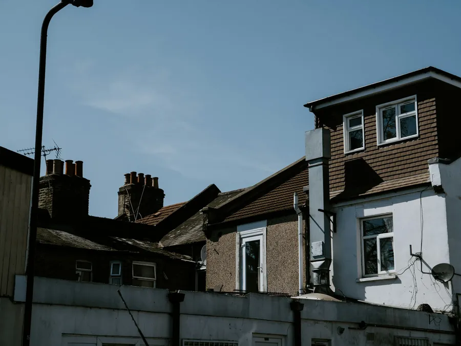 Back of a row of houses with a tile-hung dormer, chimney stacks and mixed roof slopes, details that push up a re-roof price in Dartford