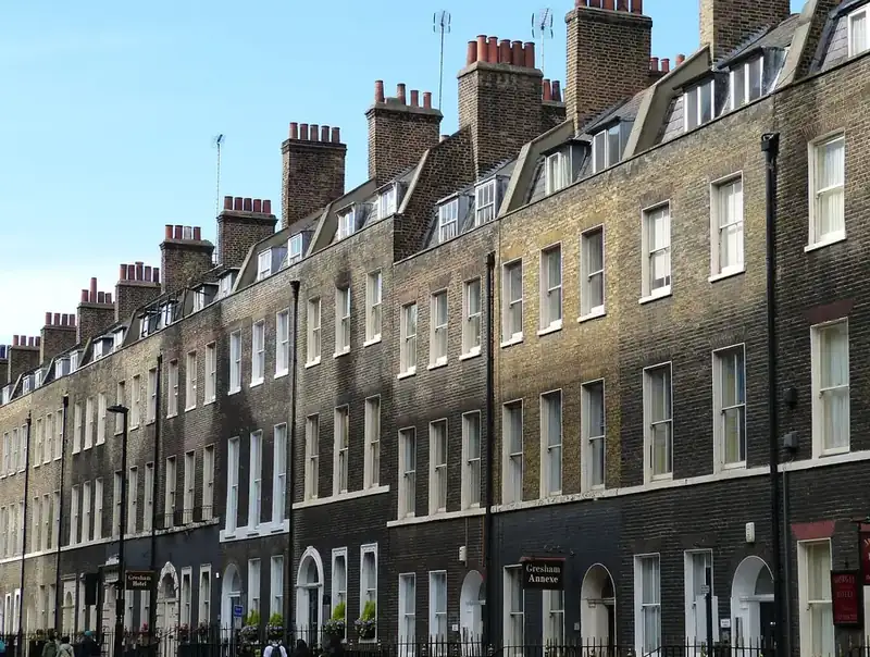 Brick terrace with a long run of dormer windows set into the roof between chimney stacks