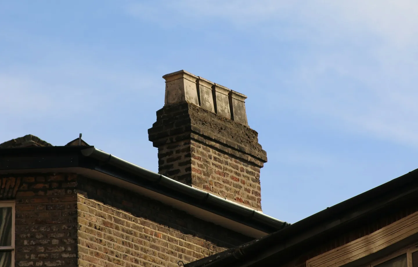 Brick chimney stack with clay pots rising above a pitched roof