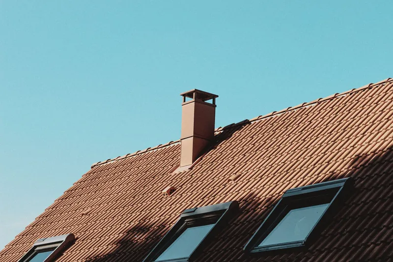 Chimney stack rising through a clay tile roof with roof windows