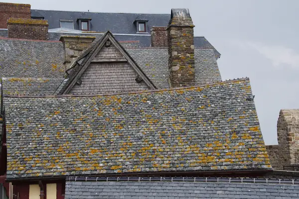 Old lichen-covered slate roofs with uneven, slipping slates