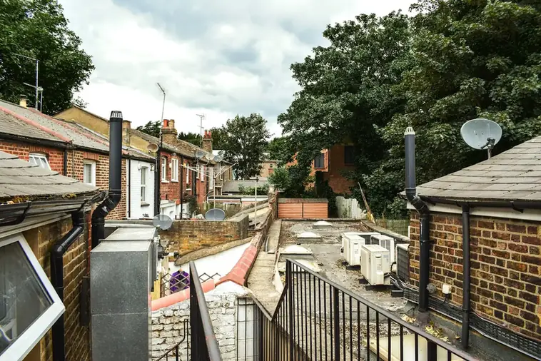 Rear extensions with flat roofs behind a row of brick terraced houses