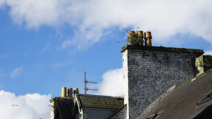 Rendered chimney stack with clay pots above neighbouring rooftops