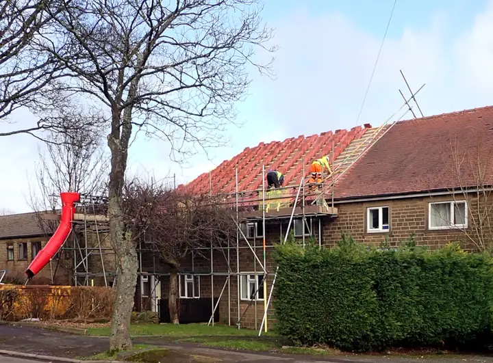 Roofers on scaffold re-tiling the roof of a pair of semi-detached houses