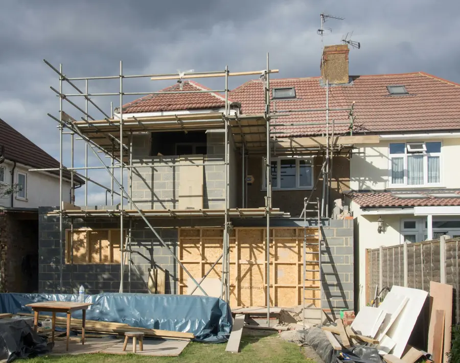 Scaffold round the back of a semi-detached house with a tiled roof and roof window