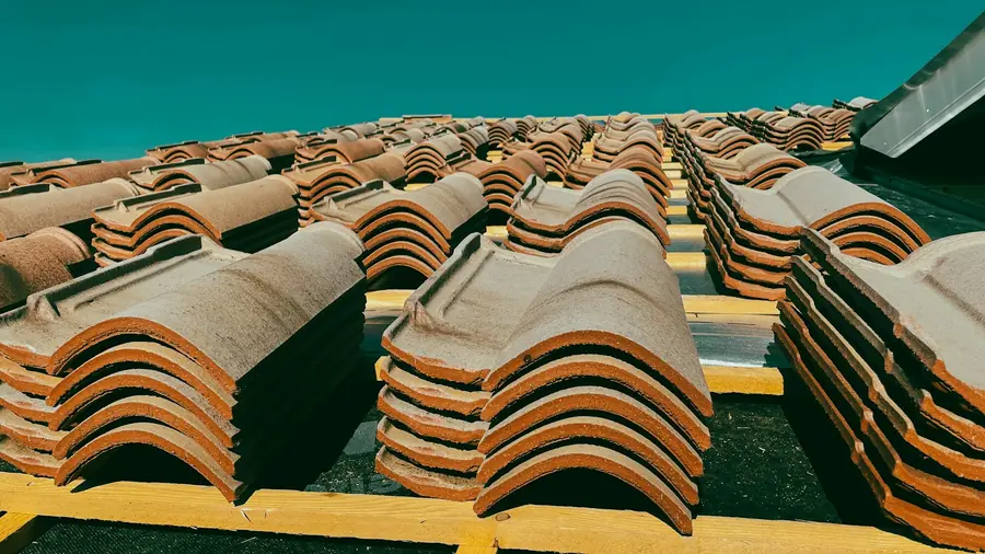 New clay roof tiles stacked in rows across battens, loaded out ready for a full re-roof