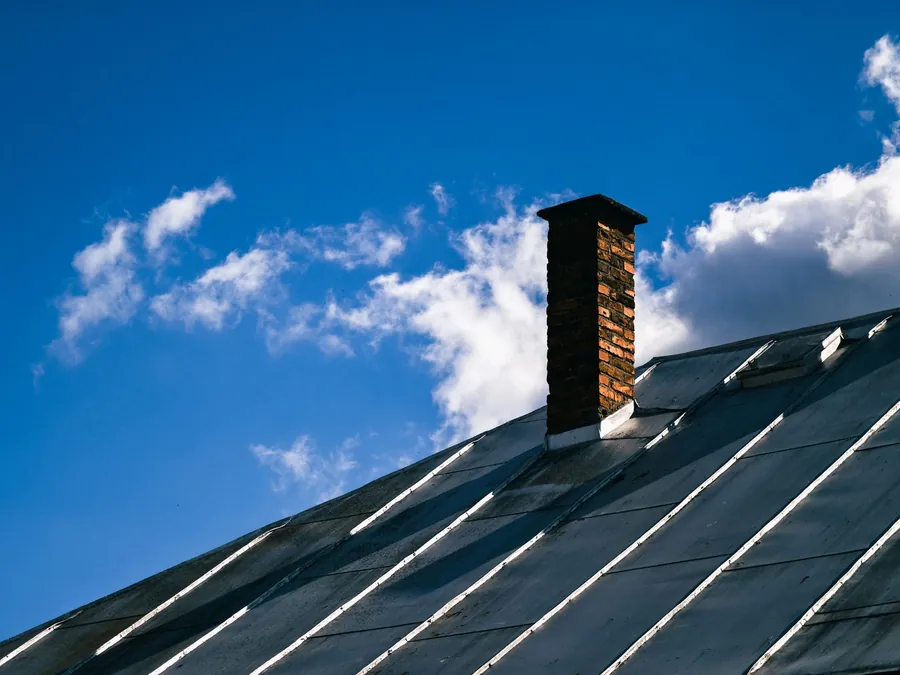 Metal standing seam roof running up to a brick chimney stack