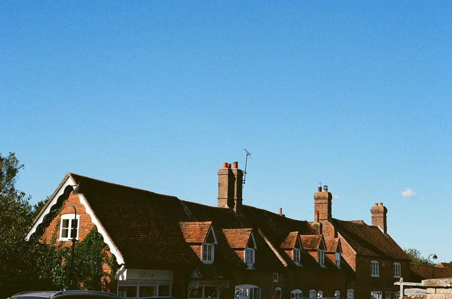 Row of brick houses with dormers and chimney stacks against a blue sky