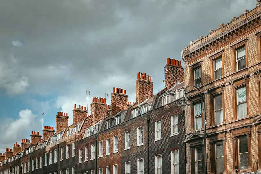 Long Georgian brick terrace with a row of chimney stacks under a cloudy sky