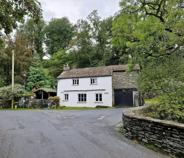 White-painted cottage with a tiled roof beside a lane