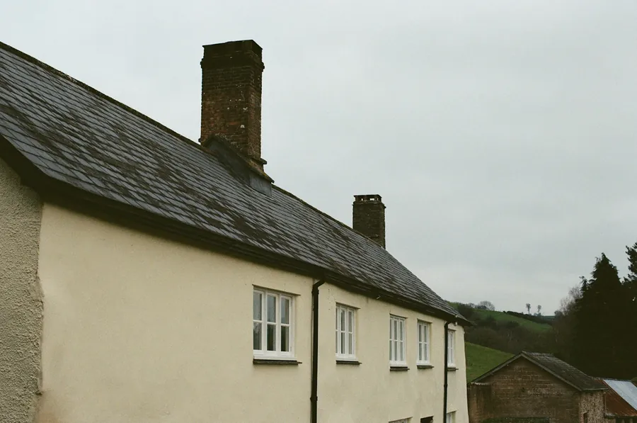 Row of rendered cottages with a slate roof and chimney
